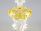 un flacon de parfum en verre transparent avec un bouchon jaune