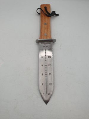 a close up of a knife on a white surface with a measuring stick