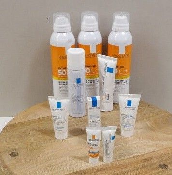 plusieurs flacons de crème solaire et de lotion posés sur un plateau en bois