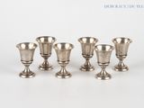 quatre vases en argent posés les uns à côté des autres sur une surface blanche