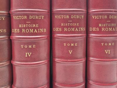 Plusieurs livres rouges sont empilés les uns sur les autres, alignés en rangée.