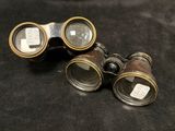 pair of antique binoculars on black cloth with tags on them