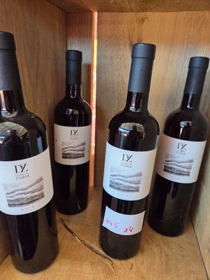 six bottles of wine are lined up on a wooden shelf