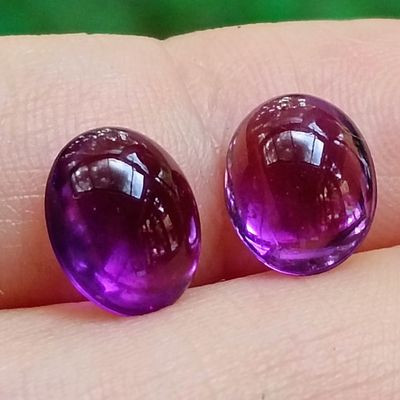 deux pierres précieuses violettes posées sur le doigt d'une personne