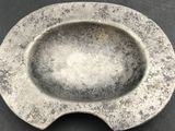 a silver ashtray sitting on a table with a black background