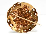 an image of a gold brooch or pin with a flower design