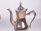 two silver teapots sitting on a white surface