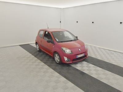 une petite voiture rouge garée dans une pièce blanche