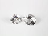 une paire de boucles d'oreilles en diamant blanc posées sur une surface blanche