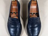 navy blue leather loafers with gold buckles on a white surface