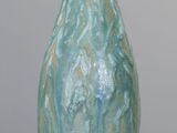 un vase bleu posé sur une table, sur fond gris