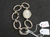 une montre attachée à une chaîne sur laquelle sont accrochés des pendentifs