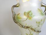 un vase blanc orné de feuilles vertes, posé sur une table