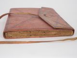 an old book with a leather strap on a white surface