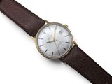 a close up of a watch on a white surface with a brown strap