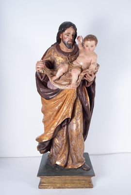 statue de Jésus tenant un enfant dans ses bras, posée sur un socle en bois