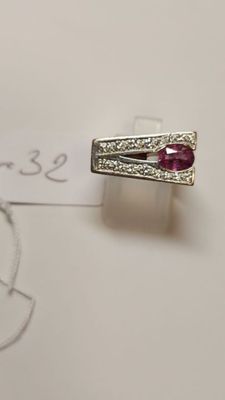 a close up of a ring with a red stone on a piece of paper