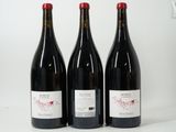 three bottles of red wine are lined up on a white surface