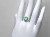 une image représentant la main d'une femme à laquelle est passée une bague verte et blanche