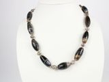un gros plan d'un collier porté par un mannequin, composé de perles noires et blanches