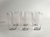 quatre verres transparents sont alignés sur une surface blanche