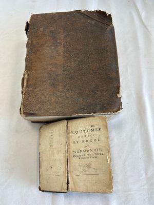 an old book sitting on top of a white sheet next to a book