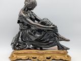 an image of a bronze statue of a woman sitting on a bench