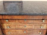 a wooden chest of drawers with a black marble top