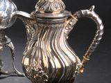 une cafetière en argent et une théière en argent posées sur un support