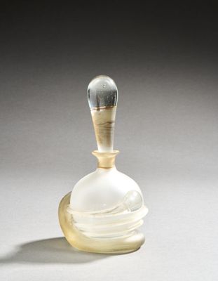 a glass perfume bottle with a gold handle on a white surface