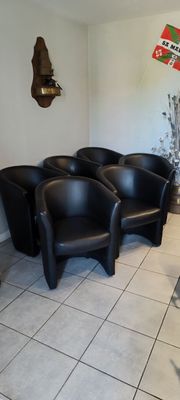 Plusieurs fauteuils en cuir noir sont alignés dans une salle d'attente