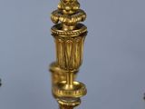 an antique brass candelier with five candles and a candle holder
