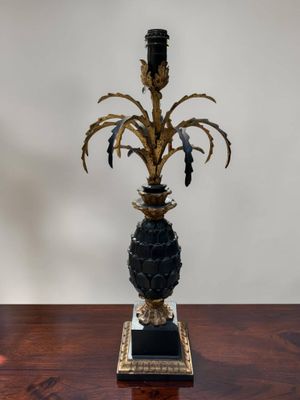 a black and gold vase with a plant on top of it