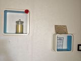 two shelves on the wall with a candle and a sign on it