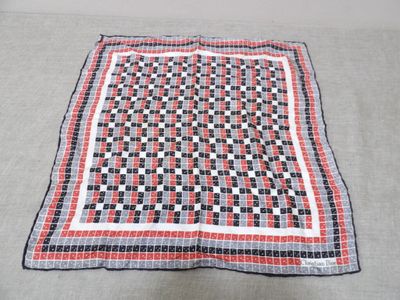 une couverture à carreaux rouges, blancs et noirs posée sur un lit