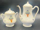 two pieces of porcelain teapots with flowers on them sitting on a table