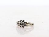 a close up of a ring with black and white diamonds on a white surface