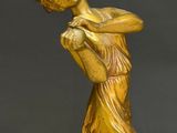 an antique bronze statue of a woman holding a ball