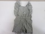 gray and white romper with ruffles on a hanger on a wall