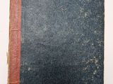 un vieux livre posé sur une surface blanche, orné d'une bande rouge