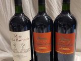 three bottles of red wine are lined up on a table