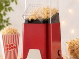 une photo d'une machine à pop-corn rouge posée sur une table en bois
