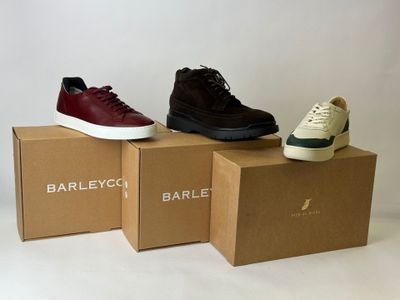 three pairs of shoes sitting on top of boxes in front of a white background