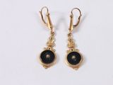 a pair of gold earrings with black stones on them