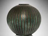 a green and brown vase sitting on a white surface
