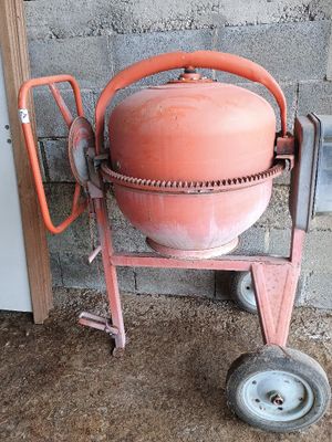 une bétonnière posée sur un chariot devant un mur de briques