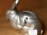a silver rabbit figurine sitting on a wooden table
