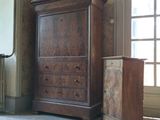 une commode et un meuble de rangement dans une pièce, sur lequel se trouve une horloge
