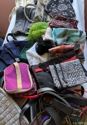 a pile of purses and handbags on a bed