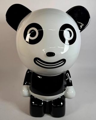 une figurine de panda noir et blanc assise sur une surface blanche